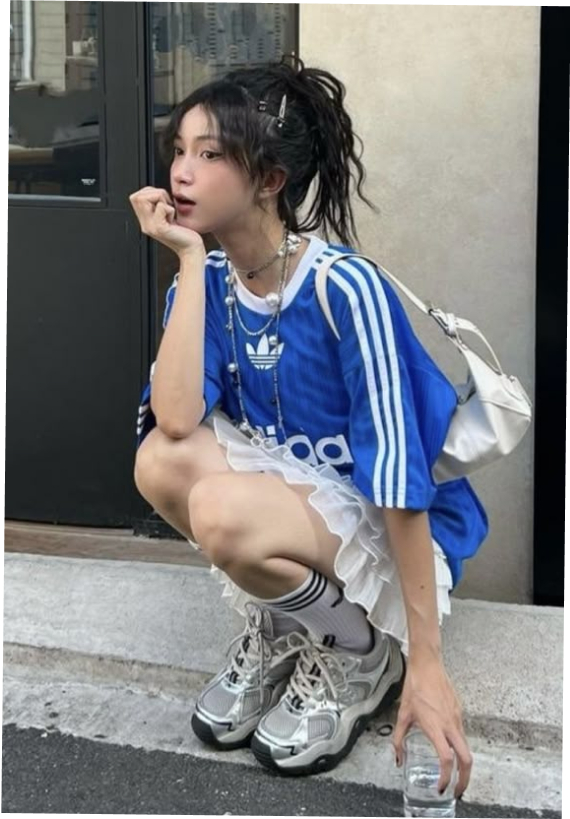 Sporty-meets-feminine street style with layered accessories, an oversized jersey, and a ruffled skirt.