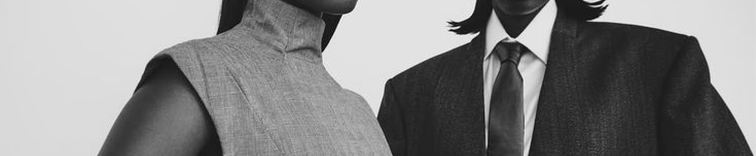 Black and white portrait of two models in structured, minimalist fashion.